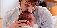 Vater drückt Baby an seine Brust