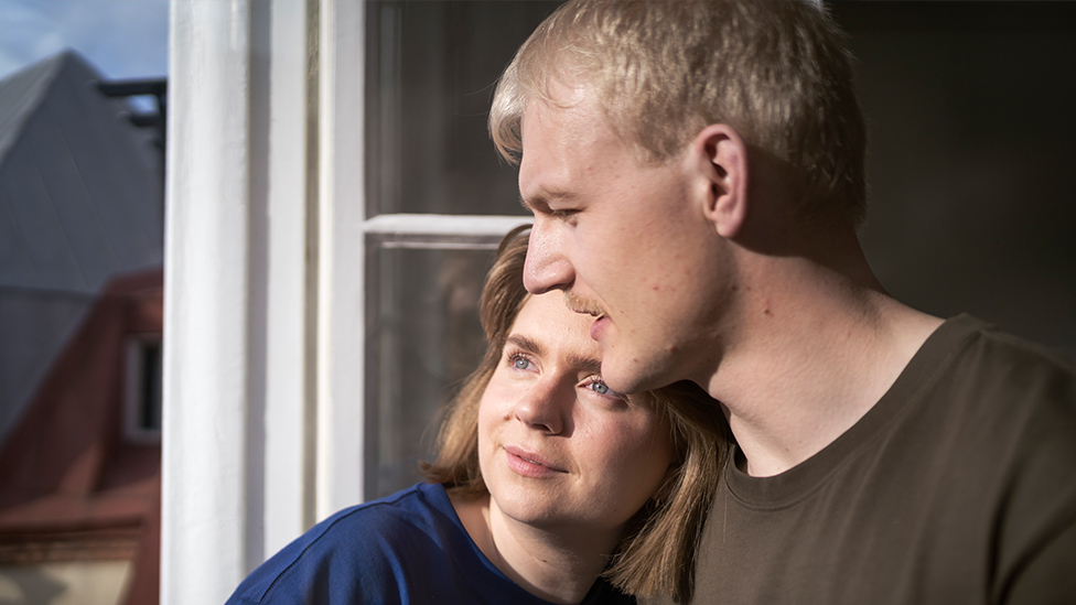 Die Chancen der Kinderwunsch-Behandlung (Quelle: Johner Images via GettyImages) Frau hat Kopf auf die Schulter des Mannes gelegt,, beide stehen am Fenster