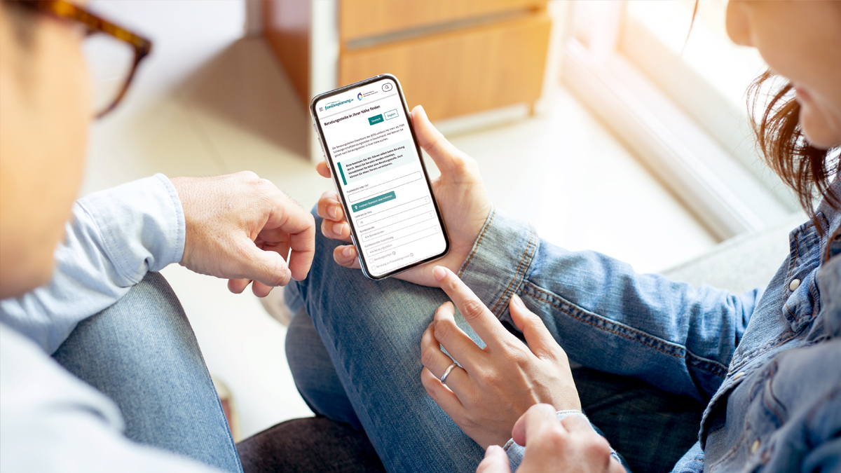 Paar schaut auf Smartphone nach Beratungsstelle