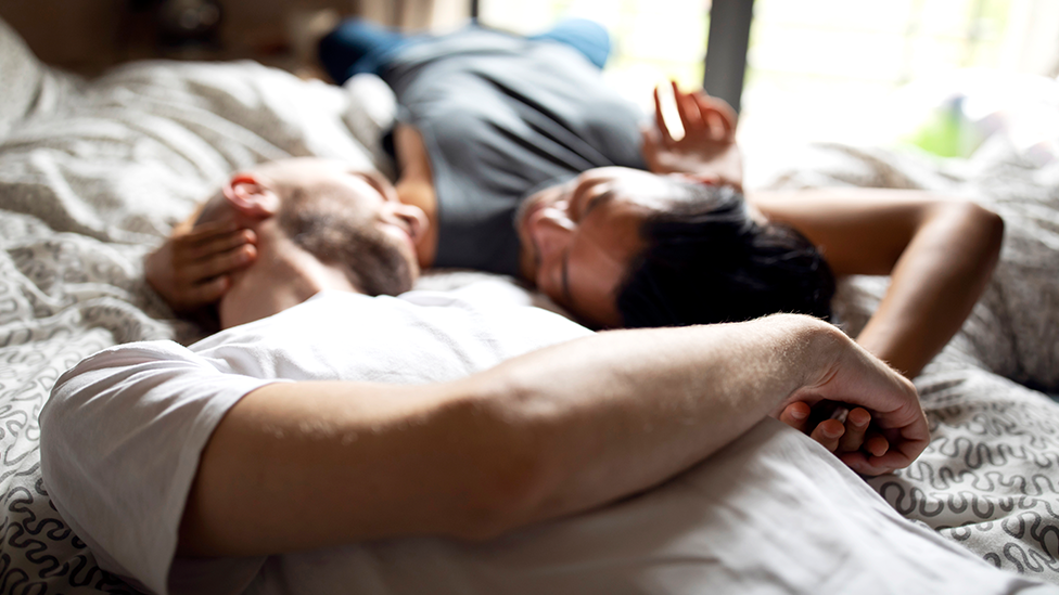 Paar liegt im Bett und schaut sich an