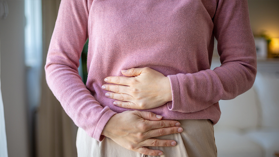 Frau hält beide Hände schützend auf ihren Unterbauch